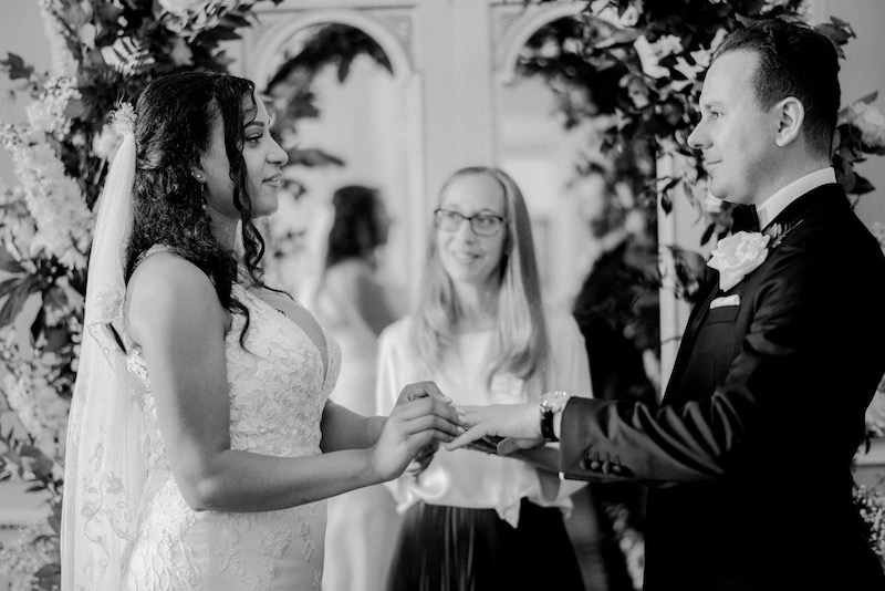 bride and groom performing a ring exchange in front of a celebrant and a floral arch at Salomon's Estate