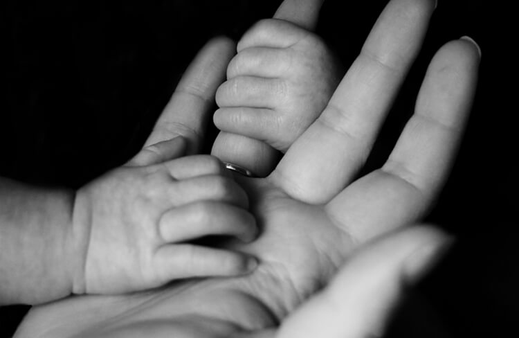 B&W image of tiny hands gripping parent's hands