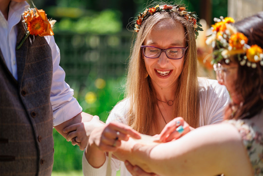 Alex Hilder Celebrant ties the handfasting cords around the hands of a couple at The Lakehouse, Kent